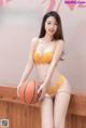 A woman in a yellow lingerie holding a basketball.