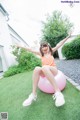 A woman sitting on an exercise ball in the grass.