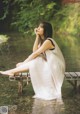 A woman sitting on a wooden bench in the water.