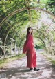 A woman in a red dress standing under a canopy of flowers.