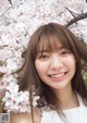 A woman standing in front of a tree with white flowers.