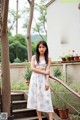 A woman in a white dress standing on some steps.