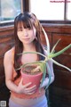 A young woman holding a potted plant in her hands.