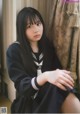 A woman in a school uniform sitting on a window sill.