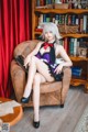 A woman sitting in a chair in front of a book shelf.