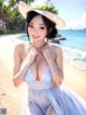 A woman in a white dress and hat on a beach.