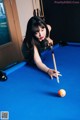 A woman leaning over a pool table with a cue.