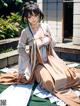 A woman in a kimono sitting on a wooden bench.