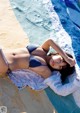 A woman in a blue bikini laying on the edge of a pool.