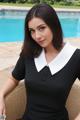 A woman in a black dress sitting by a pool.