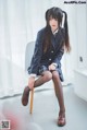 A woman in a school uniform sitting on a chair.