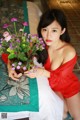 A woman in a red dress holding a bouquet of flowers.