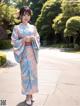 A woman in a blue and pink kimono standing on a sidewalk.