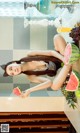 A woman sitting on top of a counter next to a bunch of fruit.