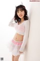 A woman in a white sweater and pink tutu posing for a picture.